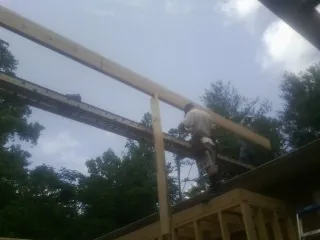 Carpenter setting a ridge beam over a new addition frame — Ice Dam Removal by Roofing Brothers in Ardenvoir