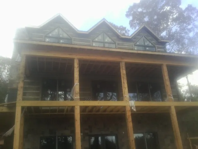 Dormers and porch framing on a large log home under construction — Roof Coating work by our crew in Ardenvoir