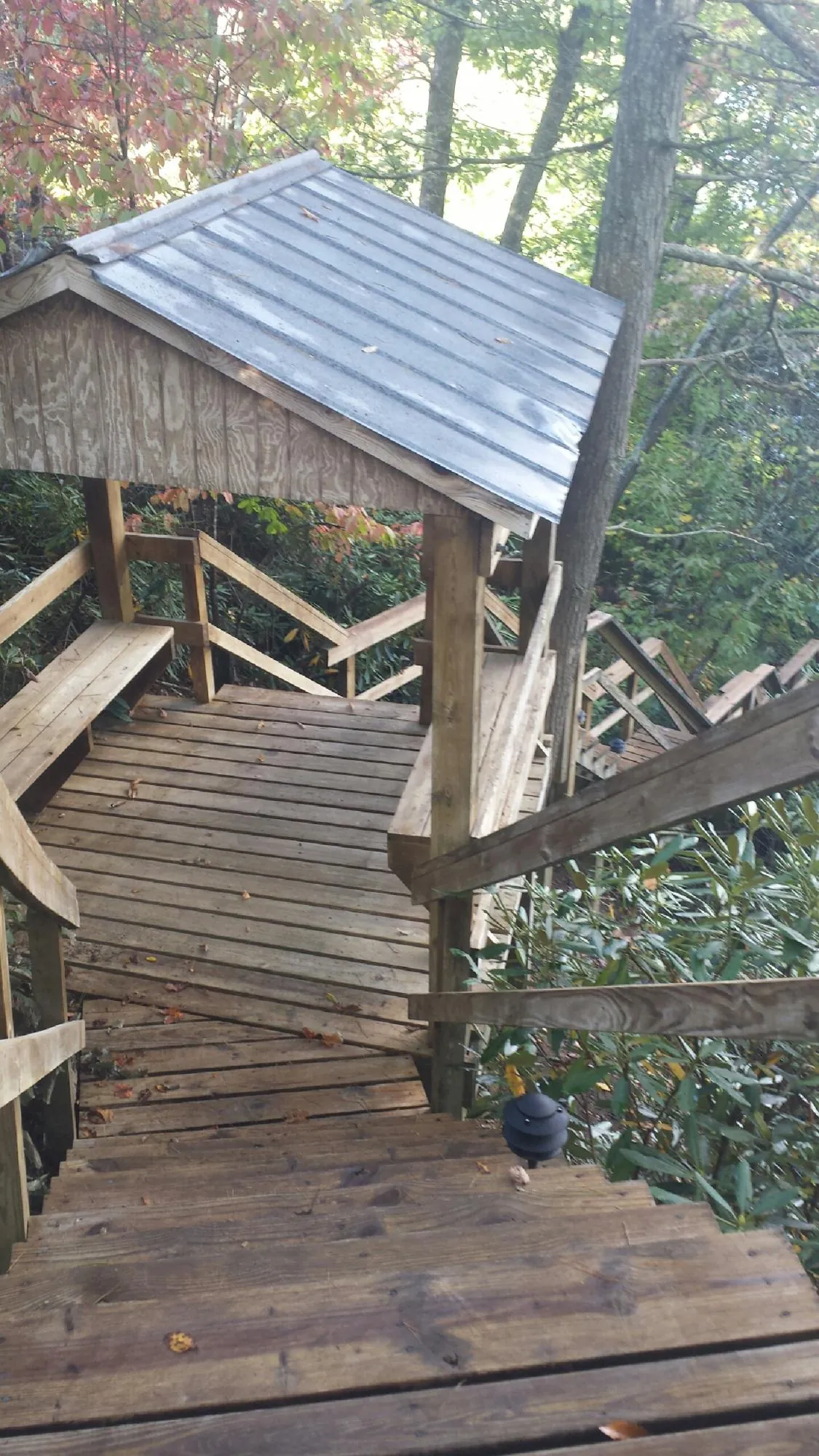 Metal roofed shelter over wooden steps on a wooded walkway — Skylight Repair & Installation work by our crew in Ardenvoir