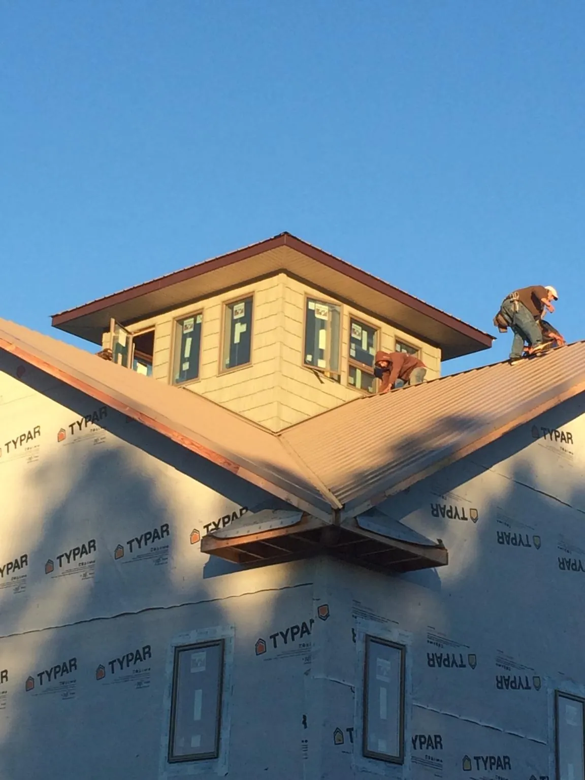 Roofers working around a rooftop cupola on a new metal roof at sunset — Roof Waterproofing in Ardenvoir by Roofing Brothers